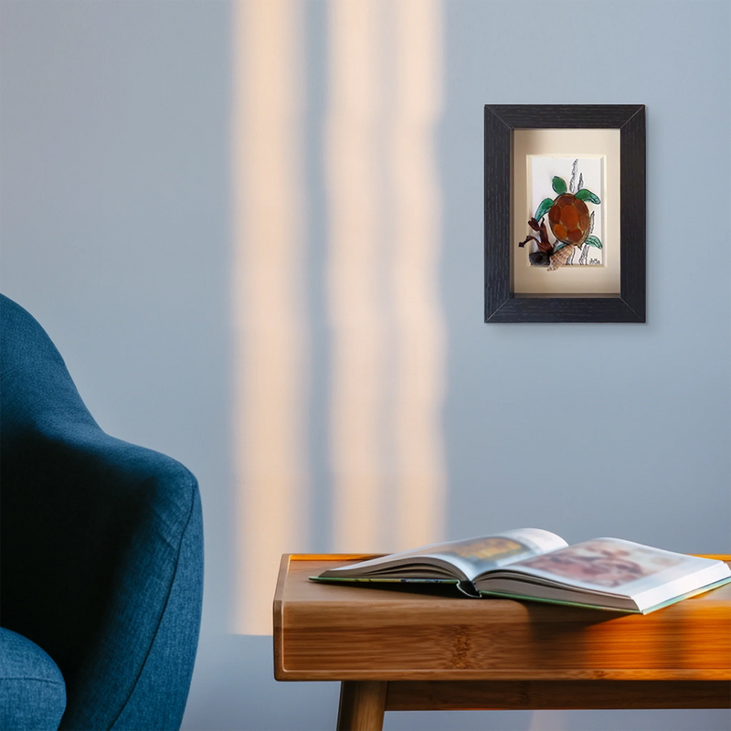 Pared de salon con estuina de butaca azul, mesita madera con libro y cuadro cristales de mar pulido de tortuga 