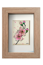 Cuadro con dibujo de rama de almendro con flores de tinta y acuarela con vidrio de mar resaltando los pétalos y los capullos