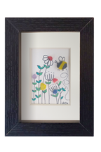 Cuadro de vidrio de mar sobre tinta y acuarela con un abejorro revoloteando entre flores silvestres de distintos colores. Marco negro