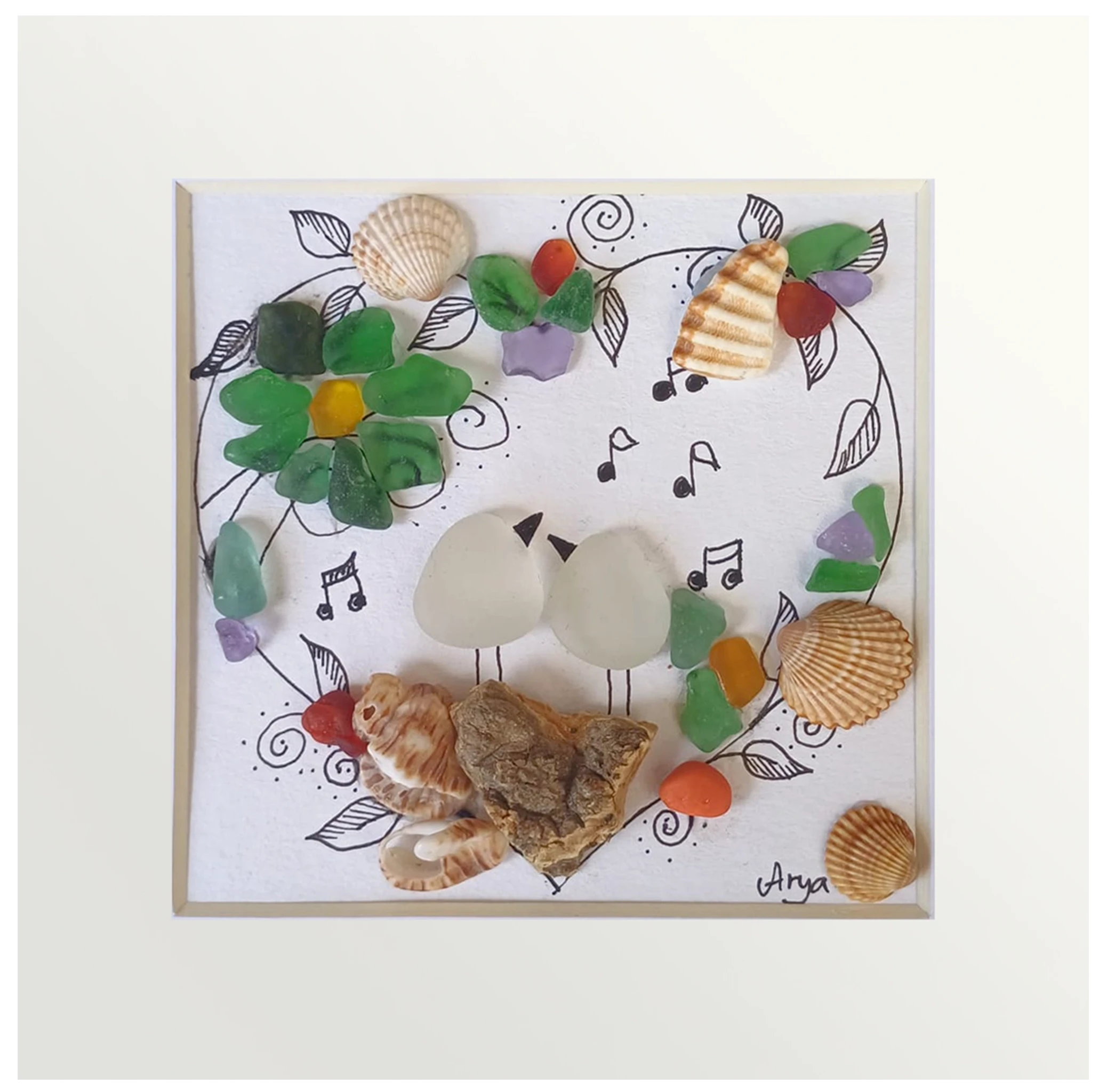 Cuadro de vidrio de mar y tinta con dos pájaros juntos dentro de un corazón de folres, música y conchas. 