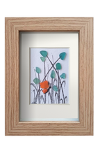 Cuadro con flores azules y una mariposa naranja hechos con tinta y vidrio de mar azlul para las flores y naranja para las alas de la mariposa