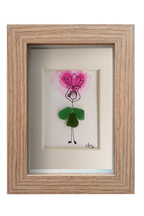 Cuadro con dibujo de chica con falda de vidrio de mar verde que sostiene sobre la cabeza una flor de loto rosada hecha con acuarela y tinta. Marco madera