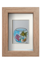Cuadro con pecera redonda con un pez betta amarillo_verdoso con decoración marina en la que se puede esconder. Acuarela, tinta y cristal de mar y conchas. Marco color madera 