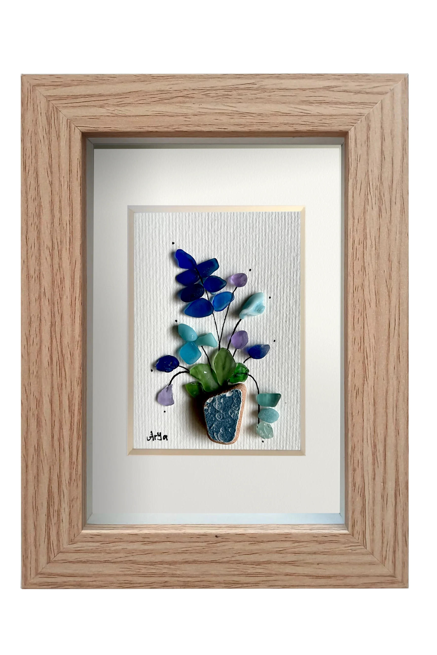 Cuadro de maceta de fragmento de ceramica erosionada de color azul petróleo con una planta de hojas verdes y flores de distintos tonos azules y lila de tinta y vidrios de mar erosionados