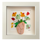Cuadro con un fragmento de cerámica desgastado a modo de maceta y una explosión de hojas y flores multicolor hechas con tinta y vidrio de mar