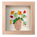 Cuadro con un fragmento de cerámica desgastado a modo de maceta y una explosión de hojas y flores multicolor hechas con tinta y vidrio de mar