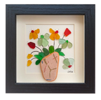 Cuadro con un fragmento de cerámica desgastado a modo de maceta y una explosión de hojas y flores multicolor hechas con tinta y vidrio de mar