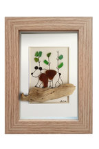 Cuadro con un fragmento de madera desgastado a modo de camino y un oso dibujado en tinta y vidrio de mar marrón, andando por un bosque adornado con vidrios verdes. Marco madera