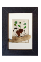 Cuadro con un fragmento de madera desgastado a modo de camino y un oso dibujado en tinta y vidrio de mar marrón, andando por un bosque adornado con vidrios verdes. Marco negro