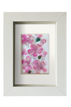 Cuadro con delicadas flores de acuarela rosa y tinta con vidrio de mar translúcido dándo volumen y vida a los pétalos. 3 capullos de vidrio verde le dan contraste a las flores rosa. Marco blanco