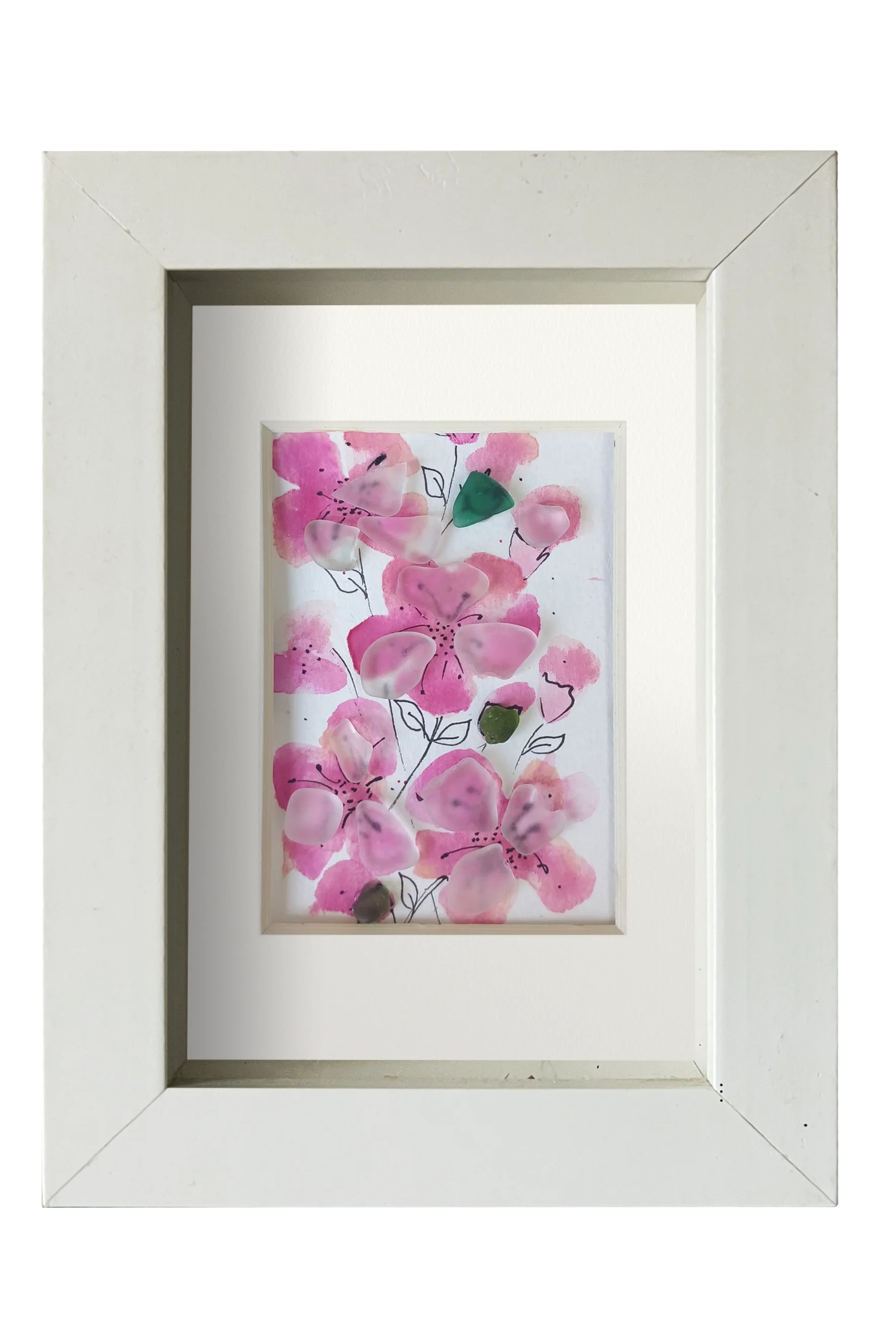 Cuadro con delicadas flores de acuarela rosa y tinta con vidrio de mar translúcido dándo volumen y vida a los pétalos. 3 capullos de vidrio verde le dan contraste a las flores rosa. Marco blanco