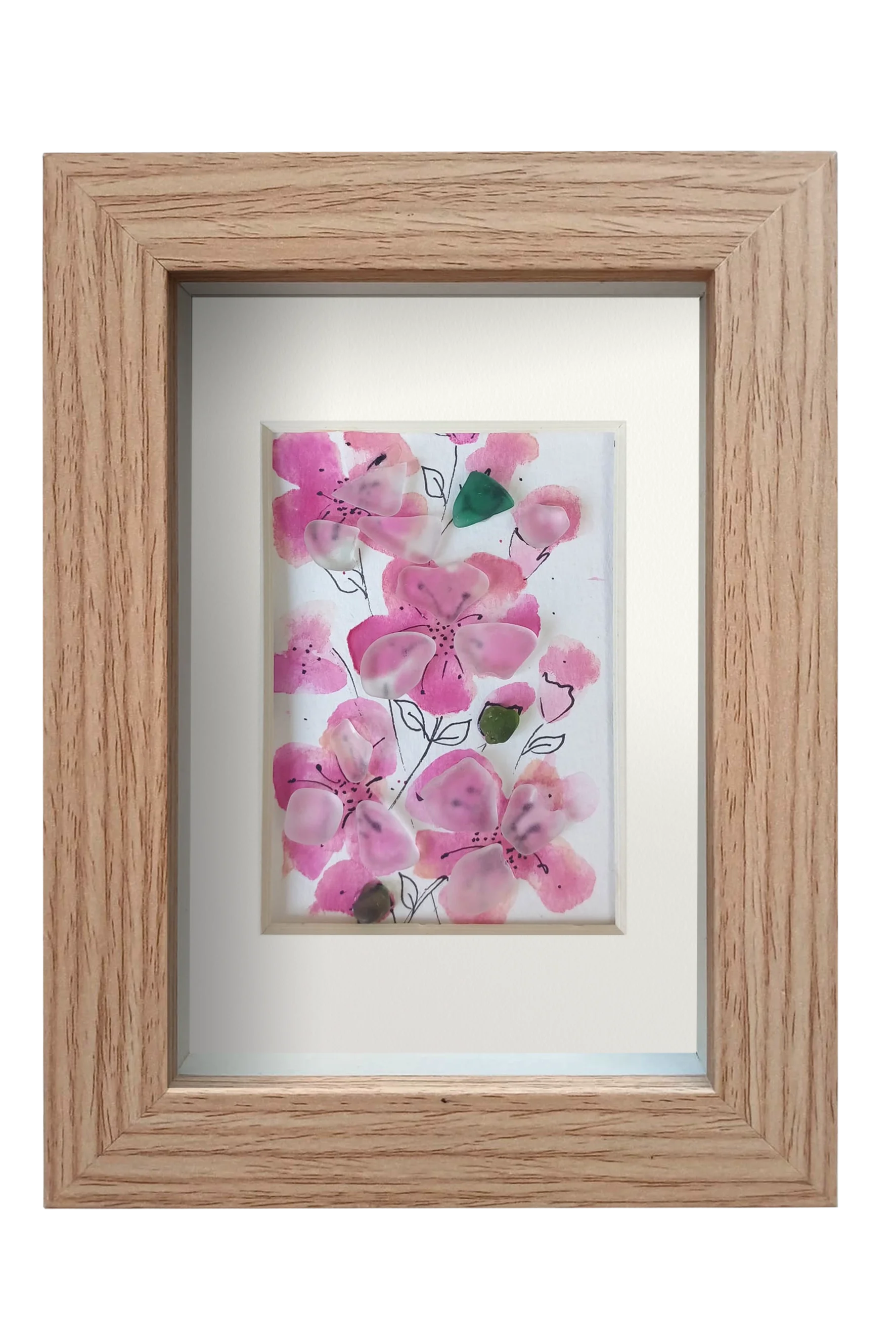 Cuadro con delicadas flores de acuarela rosa y tinta con vidrio de mar translúcido dándo volumen y vida a los pétalos. 3 capullos de vidrio verde le dan contraste a las flores rosa. Marco madera