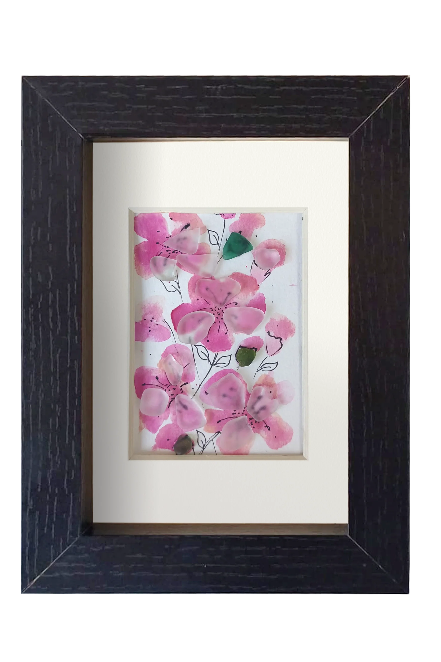 Cuadro con delicadas flores de acuarela rosa y tinta con vidrio de mar translúcido dándo volumen y vida a los pétalos. 3 capullos de vidrio verde le dan contraste a las flores rosa. Marco blanco