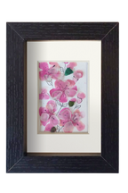 Cuadro con delicadas flores de acuarela rosa y tinta con vidrio de mar translúcido dándo volumen y vida a los pétalos. 3 capullos de vidrio verde le dan contraste a las flores rosa. Marco negro
