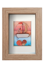 Cuadro con collage de fragmentos de cerámica, conchas y vidrio de mar de un atadecer rojizo marinero con un velero navegando en el mar en calma. Marco madera.