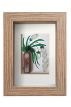 Cuadro con maceta alargada y planta con flores blancas colgantes de tinta y vidrio marino blanco para las flores y verde para las hojas