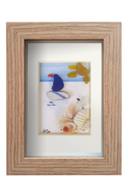 Cuadro de vidrio de mar y otros restos marinos con Pájaro observando desde la costa a un velerito en un dia soleado. Marco madera